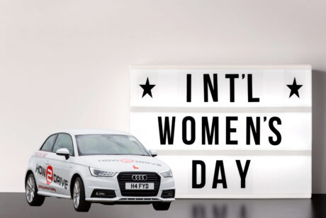 Picture showing International Women's Day sign and a How-2-Drive car