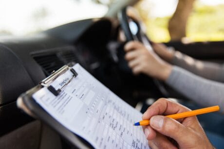 An examiner marking a learner who is taking their driving test.