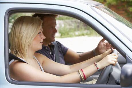 A woman taking a refresher driving lesson with her driving instructor.