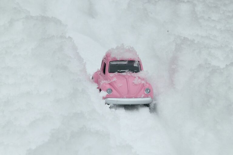 A toy VW Beetle trying to drive through deep snow.